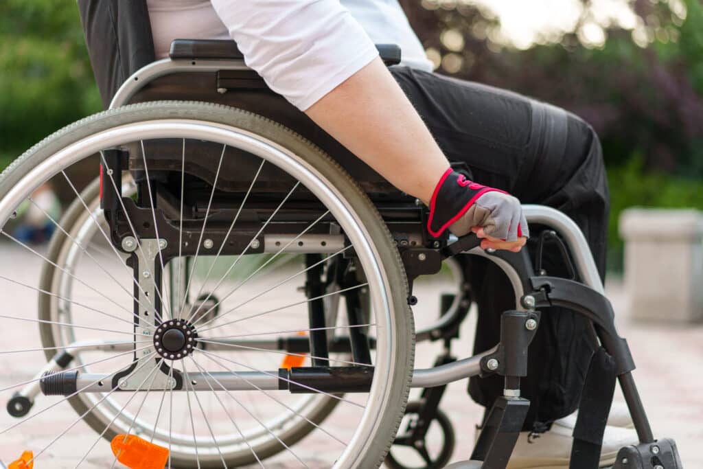 Unrecognizable woman with disability sitting in wheelchair in the street close up photo